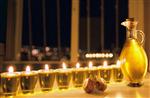 eight chanuka lights on a window-sill with a jug of olive oil and two dreidels