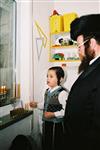 Father and Sons light Chanukah candles in the window