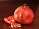 a pomegranate with its seeds on a polished mahogany background