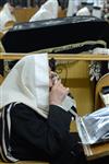 יהודים מתפללים שחרית בבית כנסת עם טלית ותפילין