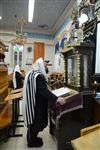 יהודים מתפללים שחרית בבית כנסת עם טלית ותפילין