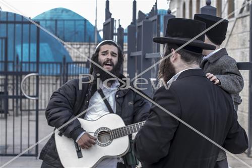 יהודי שר ומנגן לילד שחוגג טקס חלאקה במירון