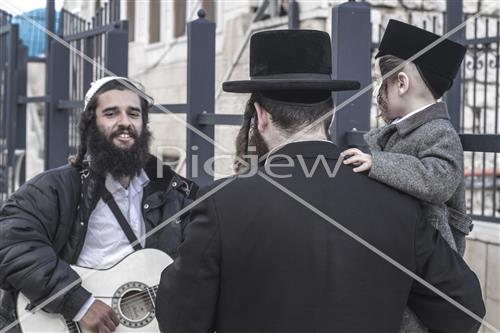 יהודי שר ומנגן לילד שחוגג טקס חלאקה במירון