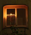 a fully lit eight branched chanuka candelabra in a window
