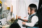 Father and Sons light Chanukah candles in the window