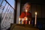 A child lights a menorah at the entrance facing the public domain