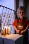 A child lights a menorah at the entrance facing the public domain