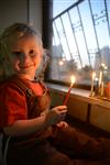 A child lights a menorah at the entrance facing the public domain