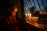 A child lights a menorah at the entrance facing the public domain