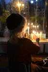 A child lights a menorah at the entrance facing the public domain