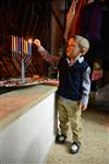 A child lights a menorah at the entrance facing the public domain