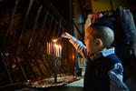 A child lights a menorah at the entrance facing the public domain