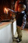 A child lights a menorah at the entrance facing the public domain