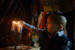 A child lights a menorah at the entrance facing the public domain