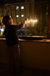 A child lights a menorah at the entrance facing the public domain