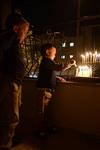 A child lights a menorah at the entrance facing the public domain