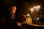 A child lights a menorah at the entrance facing the public domain