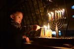 A child lights a menorah at the entrance facing the public domain