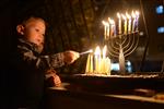 A child lights a menorah at the entrance facing the public domain