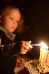 A child lights a menorah at the entrance facing the public domain