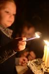 A child lights a menorah at the entrance facing the public domain