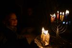 A child lights a menorah at the entrance facing the public domain