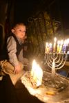 A child lights a menorah at the entrance facing the public domain