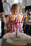 A child lights a menorah at the entrance facing the public domain