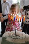 A child lights a menorah at the entrance facing the public domain