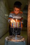 A child lights a menorah at the entrance facing the public domain