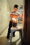 A child lights a menorah at the entrance facing the public domain