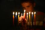 A child lights a menorah at the entrance facing the public domain