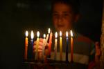 A child lights a menorah at the entrance facing the public domain