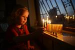 A child lights a menorah at the entrance facing the public domain