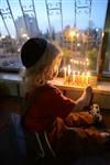 A child lights a menorah at the entrance facing the public domain