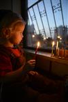 A child lights a menorah at the entrance facing the public domain