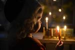 A child lights a menorah at the entrance facing the public domain