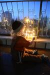 A child lights a menorah at the entrance facing the public domain