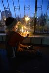 A child lights a menorah at the entrance facing the public domain