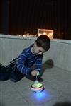 Child playing dreidel during the Hanukkah holiday by the menorah lit