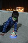 Child playing dreidel during the Hanukkah holiday by the menorah lit