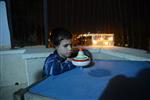 Child playing dreidel during the Hanukkah holiday by the menorah lit