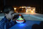 Child playing dreidel during the Hanukkah holiday by the menorah lit