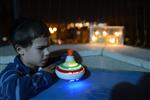 Child playing dreidel during the Hanukkah holiday by the menorah lit