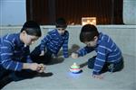 Child playing dreidel during the Hanukkah holiday by the menorah lit