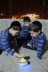 Child playing dreidel during the Hanukkah holiday by the menorah lit