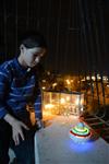 Child playing dreidel during the Hanukkah holiday by the menorah lit