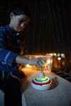 Child playing dreidel during the Hanukkah holiday by the menorah lit