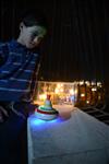 Child playing dreidel during the Hanukkah holiday by the menorah lit