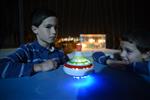 Child playing dreidel during the Hanukkah holiday by the menorah lit